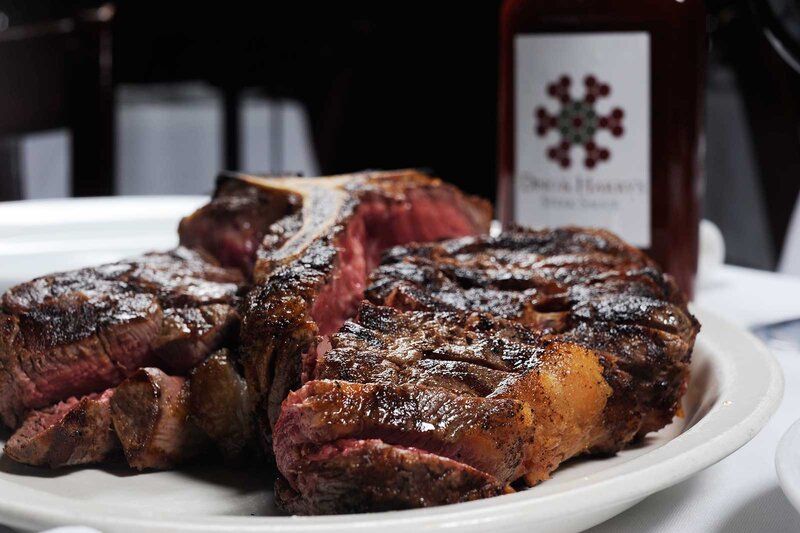 Close up of plated steak with Dino and Harry's logo in the background