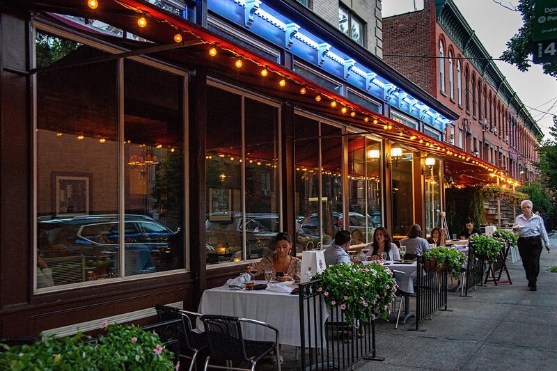 Outdoor seating with multiple set tables and guests eating